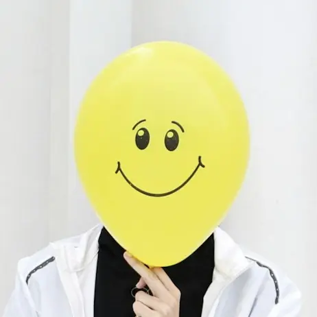 a person with a smiley face mask sitting on a wall